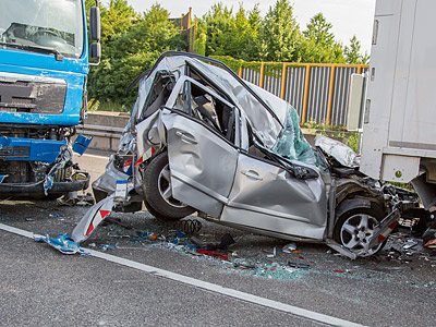 Ein schwer beschädigtes Auto nach einem Unfall mit einem Lkw auf der Straße.
